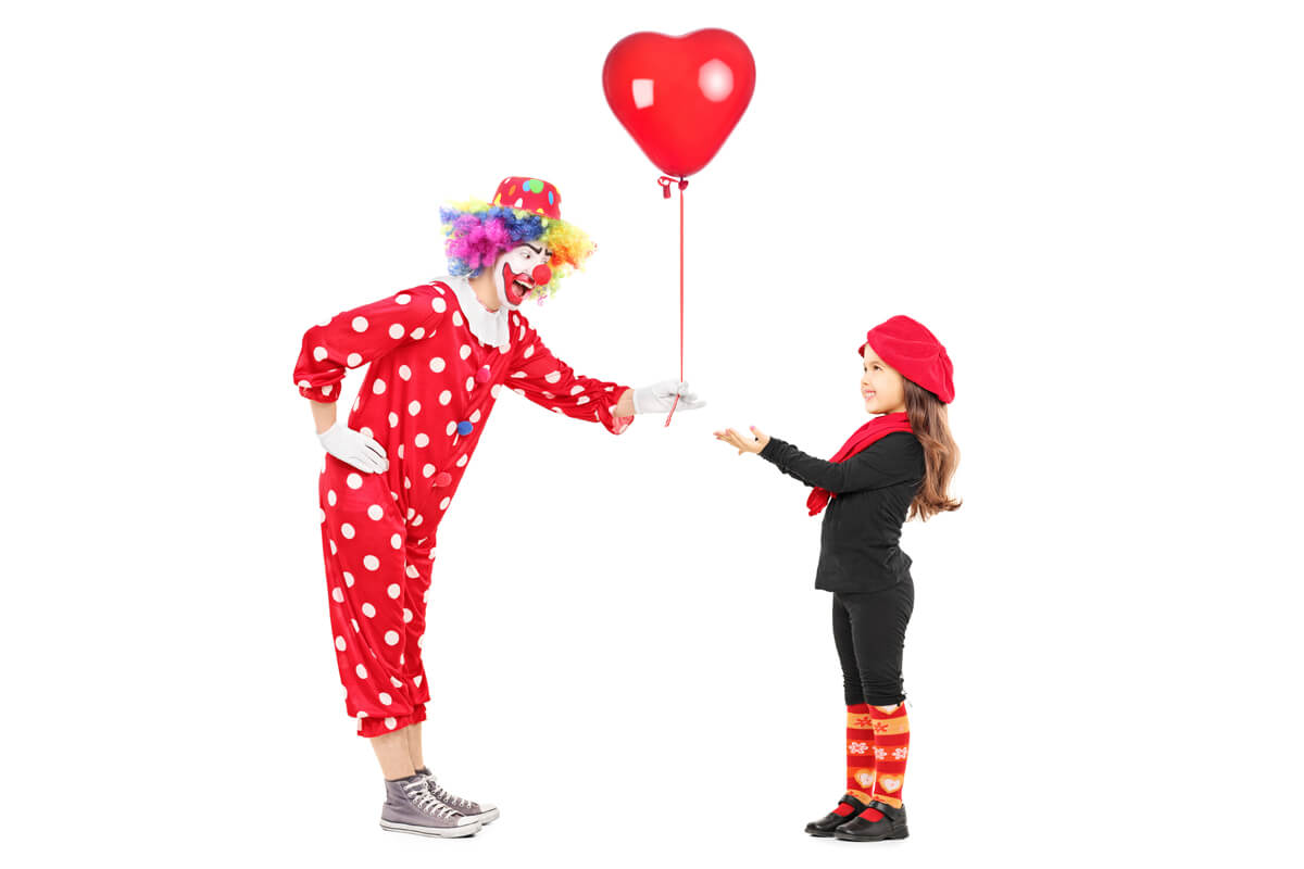 Male clown giving a red balloon to a little girl